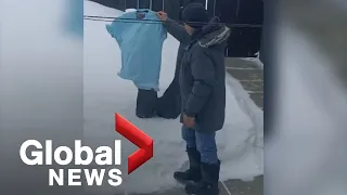 Manitoba man hangs frozen laundry before winter storm creates snowy conditions