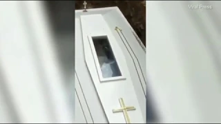 Corpse appears to way to mourners through coffin glass panel
