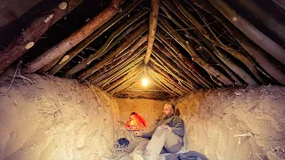 Underground Bushcraft shelter, Wilderness survival shelter, Warm shelter with fireplace in winter