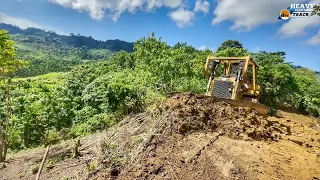 Skilled D6R XL paint bulldozer operator leveling ground for road construction on steep mountain
