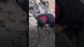 Palestinian man searches through rubble for family