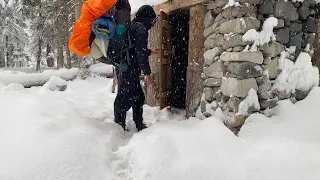 Building a stone and wood survival shelter in the woods when a snowstorm hit out of nowhere