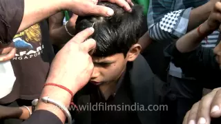 Young Shiite Muslim boy cries as an elder makes a cut on his forehead during Muharram