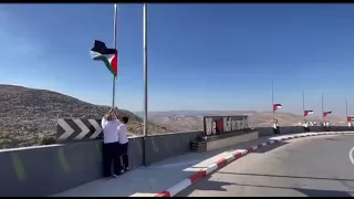 Young Palestinians raise a row of Palestinian flags at the entrance to the village of Kafr Malik