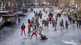 Ice skaters glide over frozen canal in Amsterdam