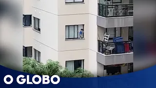 Criança é filmada pendurada em janela de edifício por vizinhos