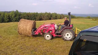 Compact tractor moving round bales of hay. TYM 353 and 4x5 bales