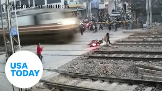 Lucky biker narrowly avoids being hit by train in northern India | USA TODAY