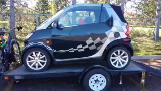 Smart car hauled on trailer