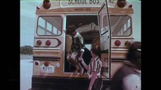 Boy helps students exit from the back of a school bus, 1970s