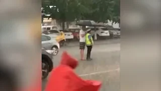 Touching moment: Man holds umbrella for traffic warden during heavy rain