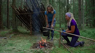 Woman bushcraft. Two girls are building a shelter in the forest. Cook a turkey on a fire