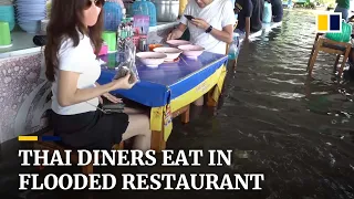 Diners in Thailand enjoy meal in flooded restaurant amid heavy rain season