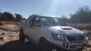 Toyota Hilux crosses some rocky terrain