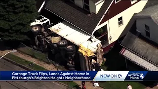 Garbage truck crashes, lands against house in Pittsburgh