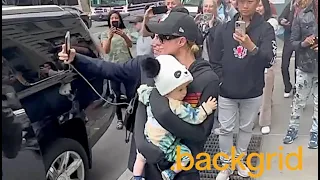 Paris Hilton stops for a selfie with a fan while holding her son Phoenix.