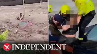 Woman clings to roof of car as flash floods wash vehicles away in Spain