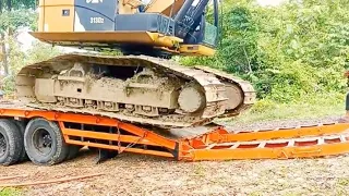 The process of lifting and lowering a Caterpillar excavator onto a self-loader.