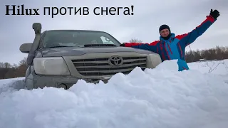 Тойота Hilux пробивает дорогу в глубоком снегу.