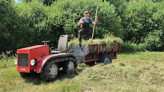 Гусеничный минитрактор косит и возит траву в компостную яму.