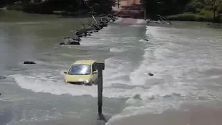 Small car takes on notorious river crossing as croc swims past