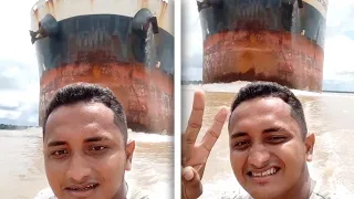 Tiny Fishing Boat Sails In Front Of Enormous CARGO SHIP