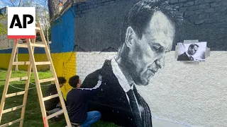 Artists spray-paint portraits of Alexei Navalny behind Soviet monument in Vienna