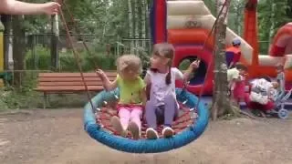 Дети катаются с горки, качаются на качелях на детской площадке в парке.