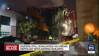 Dozens still evacuated as crews demolish smoldering building