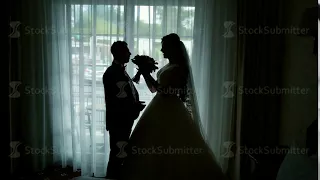 silhouettes of the bride and groom on the window background