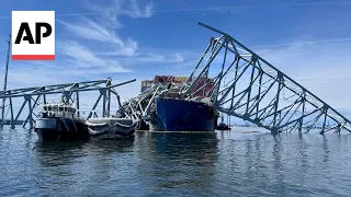 View of cargo ship and collapsed Baltimore bridge from Coast Guard boat as recovery effort continues