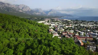 Aerial drone shot of Kemer surrounded by green mountains on one side and sea on another one