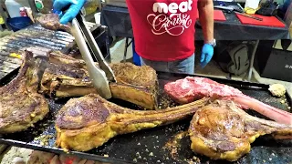 Street Food in Valencia, Spain. Grilling Giant Tomahawk Ribeye Steaks. Black Angus. Meat Carnival