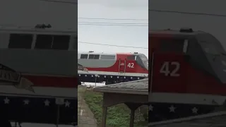 Amtrak veterans heritage unit speeds by on elevated tracks.