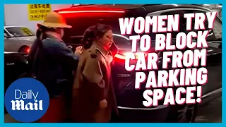 Crazy moment women try to stop MOVING CAR from taking parking space