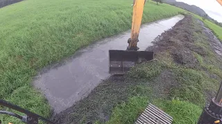 Escavadeira hidraulica limpando vala com concha de limpeza