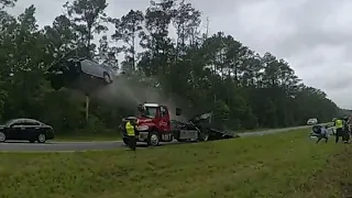 Driver sends car flying off parked tow truck ramp in front of police | Body cam