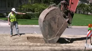 EXCAVATOR EXPOSES STORMSEWER -- REMOVES COVER