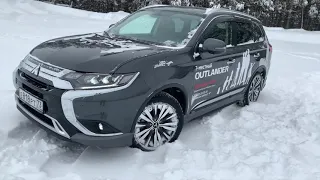 Mitsubishi Outlander 2020 уверенно едет по заметенной трассе.