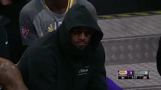 LeBron James enjoys his popcorn while sitting on the bench for the Lakers-Spurs game