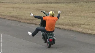 Scooter Stuntman riding no hands Vespa wheely on Airport