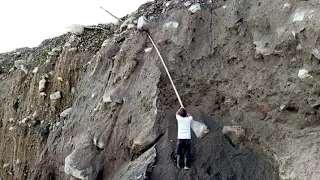 Dangerous Rocks on Top of Cliffs Are Dropped Using Long Bamboo Spears