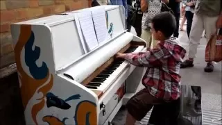 10 year old George Harliono playing street piano at a train station