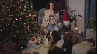 beautiful concentrated caucasian girl knitting in front of fireplace and christmas tree big moscow