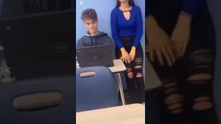 girl shoves boy out of a desk