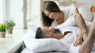 Young beautiful and loving couple wake up at the morning. Attractive woman kiss and hug his husband