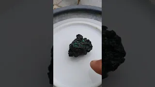 roca extraña con esquirlas verdosas  con apariencia de meteorito