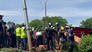 Emergency crews work to free trapped man in collapsed construction hole