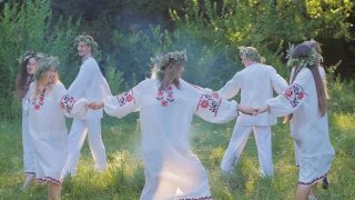 a group of young people in national Slavic costumes dance in a circle around the fire. National