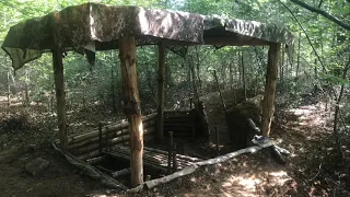 Bushcraft shelter with whattle and daub fireplace and raised bed complete build